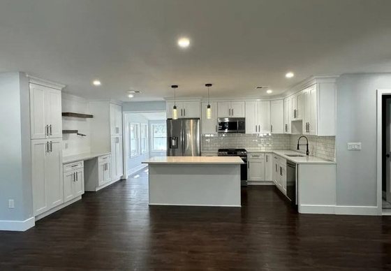 Open kitchen with white cabinets, a center island, and dark hardwood floors